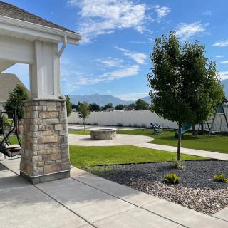 A well-maintained backyard with a patio, trees, and a view of the mountains under a clear blue sky.