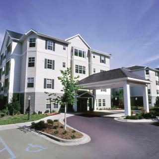 A multi-story residential building with a covered entrance and landscaped surroundings.