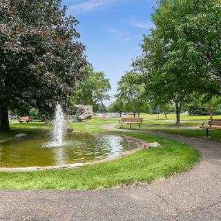 A serene park featuring a tranquil fountain surrounded by lush greenery.