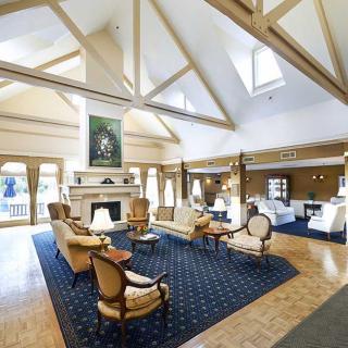 A spacious lobby with comfortable seating and a large fireplace, illuminated by natural light from skylights.