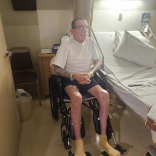A patient seated in a wheelchair in a hospital room, indicating recovery.