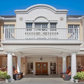 A grand entrance of a residential building with columns and a balcony.