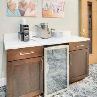 A modern coffee station with an espresso machine, coffee pods, and a beverage fridge on a countertop.