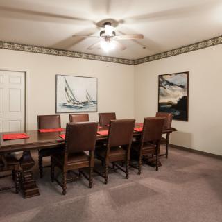 A spacious dining or conference room with a large table, eight chairs, and artwork on the walls.