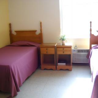 A simple bedroom with two twin beds and a shared nightstand.