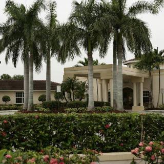 A tropical building surrounded by palm trees and a well-maintained garden.
