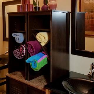 A stylish bathroom storage unit showcasing neatly rolled towels in various colors.