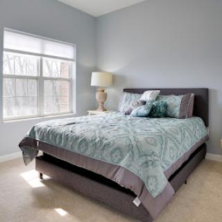A cozy and well-decorated bedroom featuring a comfortable bed and stylish lamp.