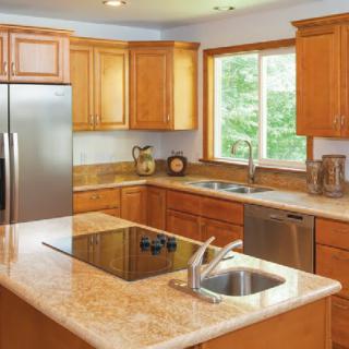 A modern kitchen featuring wooden cabinets, a marble countertop, and stainless steel appliances.