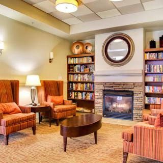 A cozy living room with a fireplace, armchairs, and bookshelves.