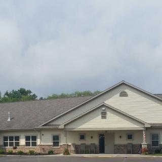 A single-story building with a gabled roof and a cloudy sky overhead.