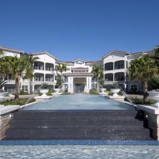A luxurious resort building with palm trees and a grand entrance under a clear blue sky.