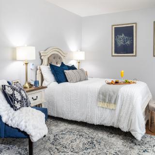 A cozy bedroom with white bedding, blue accents, and elegant decor.
