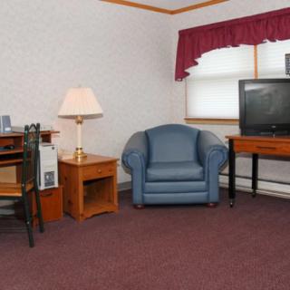 A cozy living room with a blue armchair, wooden desk, and a television set.