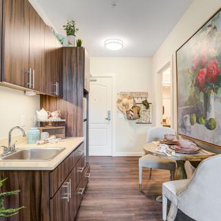 A modern kitchen with wooden cabinets and a cozy dining area, adorned with stylish decor and artwork.