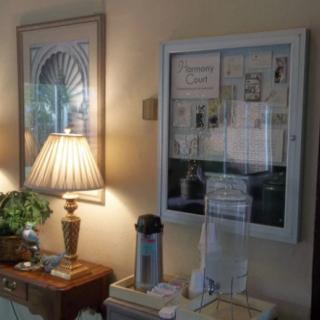 A cozy interior setting featuring a lamp, artwork on the walls, and a small wooden table with various items arranged neatly.