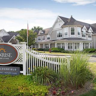 A residential-style building with a well-maintained garden and signage in the foreground.