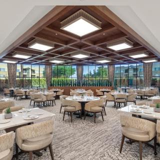 A spacious and elegantly designed dining area featuring modern furnishings and large windows that allow for plenty of natural light.