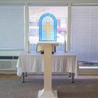 A church altar with a stained glass window featuring a cross.