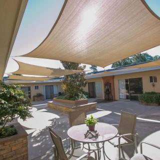 A sunny courtyard with shade sails and outdoor seating.
