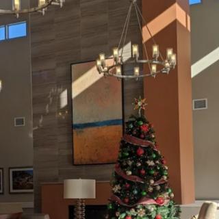 A warmly lit interior with a decorated Christmas tree and elegant chandeliers.