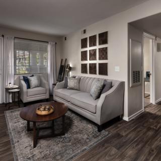 A modern living room with a cozy sofa set, armchair, and a wooden coffee table on a patterned rug.