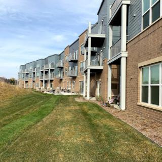 A row of modern apartments with a well-maintained lawn and clear blue sky.