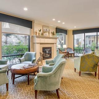 A cozy living room with comfortable seating around a fireplace and large windows.