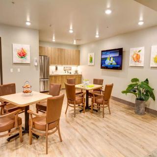 A modern dining area with wooden furniture, decorative artwork, and a television mounted on the wall.