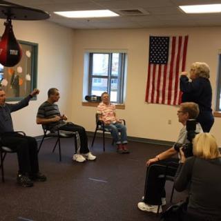 A group of seniors participating in a physical activity session, focusing on exercise and rehabilitation with a boxing bag in the background.