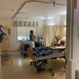 A nurse attending to a patient in a hospital room, surrounded by flowers.