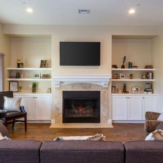 A cozy living room with a fireplace and built-in shelves, featuring a wall-mounted TV.