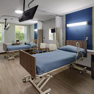 A modern hospital room with two patient beds, equipped with medical amenities.