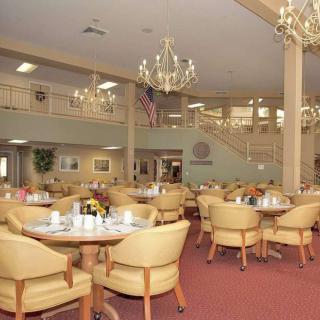 A spacious dining hall with elegant chandeliers, tables, and chairs arranged neatly.