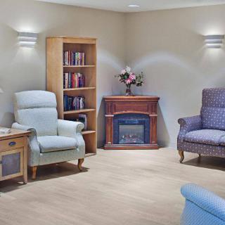 A cozy living room with comfortable seating, a bookshelf, and an electric fireplace.