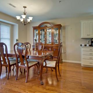 A classic dining room with a wooden table, chairs, and a cabinet on a hardwood floor.