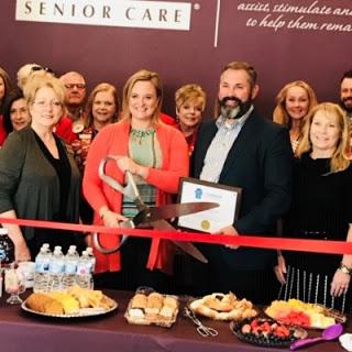 A joyful ribbon-cutting ceremony celebrating the opening of a new senior care facility, with community members gathered to show support.