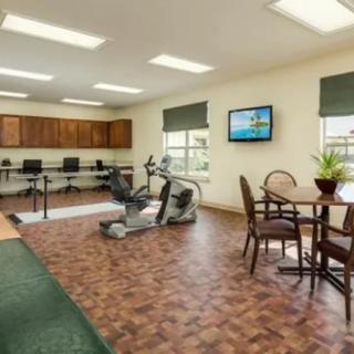 A multipurpose fitness room equipped with exercise machines, a computer area, and a TV.