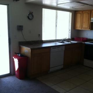A kitchen interior featuring wooden cabinets, a dishwasher, stove, and a window allowing natural light.