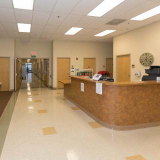 A reception area with a wooden desk and hallway in an office building.