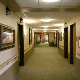 A well-lit corridor with framed artwork on the walls and multiple doors along its length.