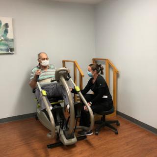 A patient engages in rehabilitation exercise with the assistance of a healthcare professional.