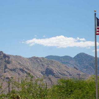 A scenic view of mountains with a clear blue sky and an American flag waving in the foreground.