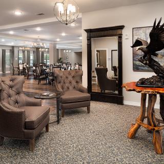 A well-appointed lounge area featuring comfortable seating, a large mirror, and a striking art sculpture on a wooden table.