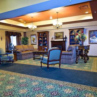 A cozy lobby interior with comfortable armchairs and a sofa, featuring elegant decor and a patterned carpet.