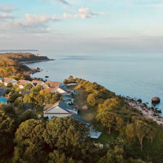 A serene coastal landscape showcasing a shoreline dotted with greenery and resort buildings, captured from an aerial perspective.