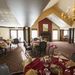 A well-decorated dining room with tables set for guests, featuring a fireplace and chandelier.