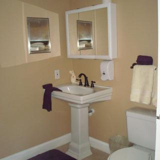 A small bathroom with a pedestal sink, mirror, and neatly arranged towels.