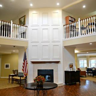 A spacious living room with a central fireplace, high ceilings, and a balcony overlooking the area.