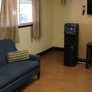 A cozy waiting room with a sofa, water cooler, and television.